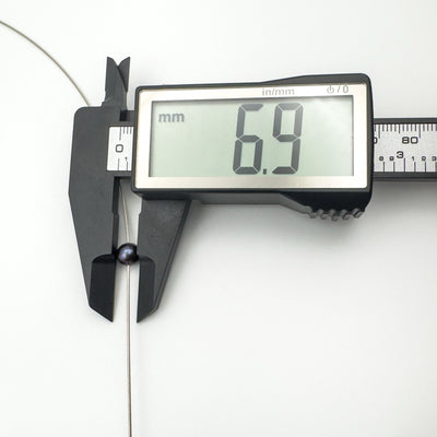 Digital caliper showing black pearl pendant measures 6.9mm diameter