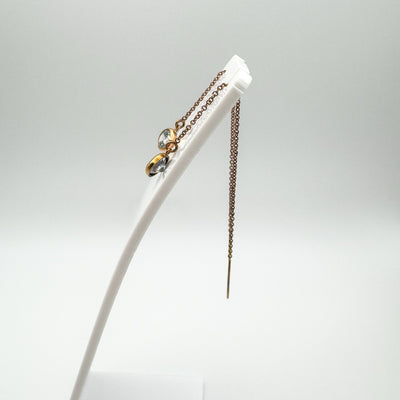 Side view of rose gold plated threader earrings on display stand