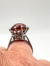 Close-up of raised carnelian solitaire ring worn on finger in silver mount