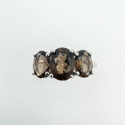 Close up of Smokey Quartz trilogy ring showing faceted oval gemstones and prong setting