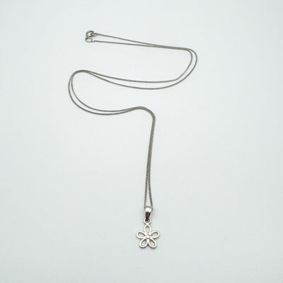 Sterling silver necklace with a small flower pendant laid flat on a white background.